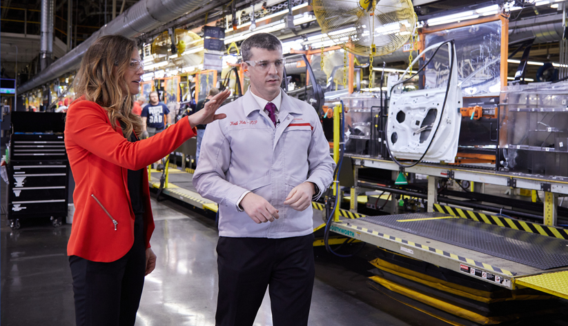 Man and woman standing in front of car assembly line